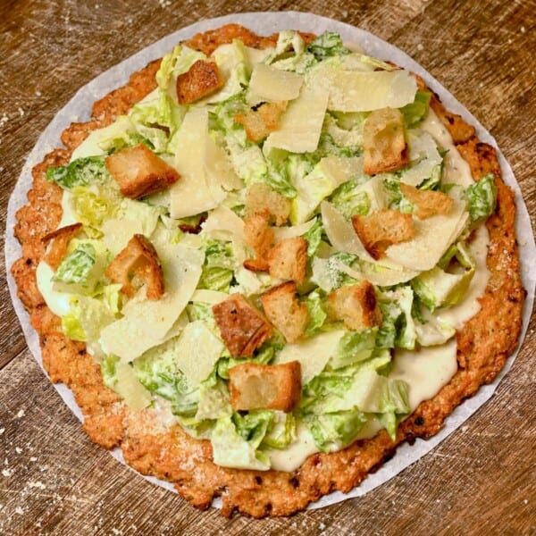 Chicken curst pizza topped with Caesar salad