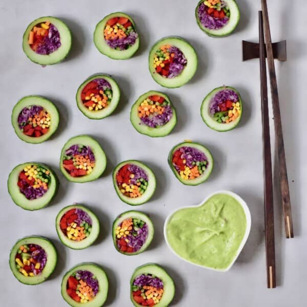 Slices of cucumber sushi stuffed with vegetables with avocado dipping sauce and chopsticks